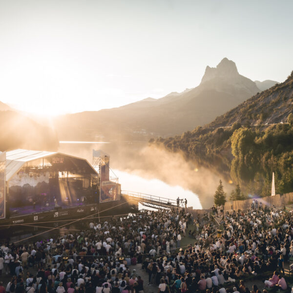 Escenario flotante de Pirineos Sur al atardecer con el público y montañas de fondo.