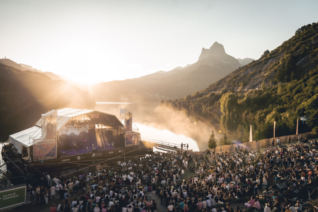 Escenario flotante de Pirineos Sur al atardecer con el público y montañas de fondo.
