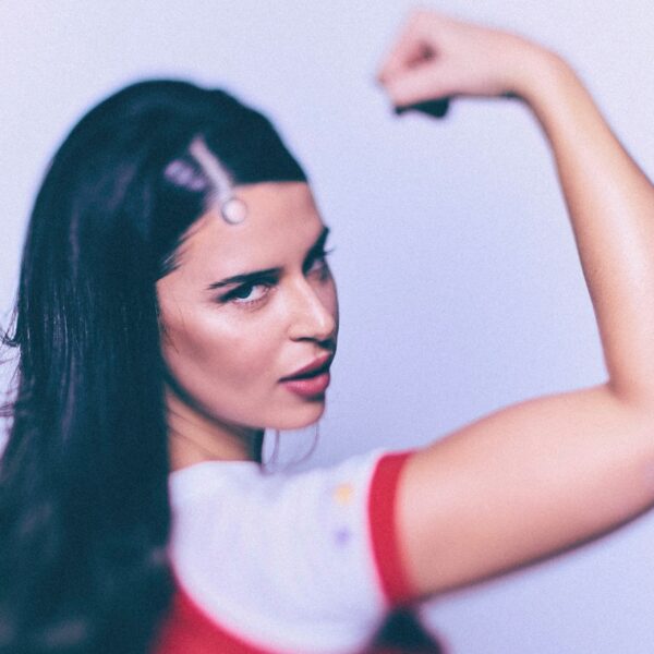 Nathy Peluso en primer plano, levantando el brazo en pose de fuerza.