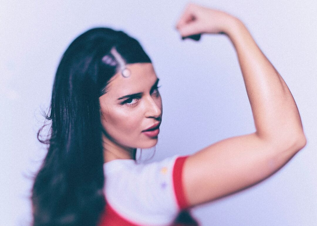 Nathy Peluso en primer plano, levantando el brazo en pose de fuerza.