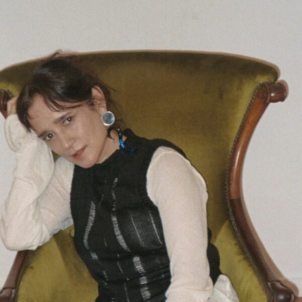 La artista Julieta Vengas sentada en un sofá individual antiguo.