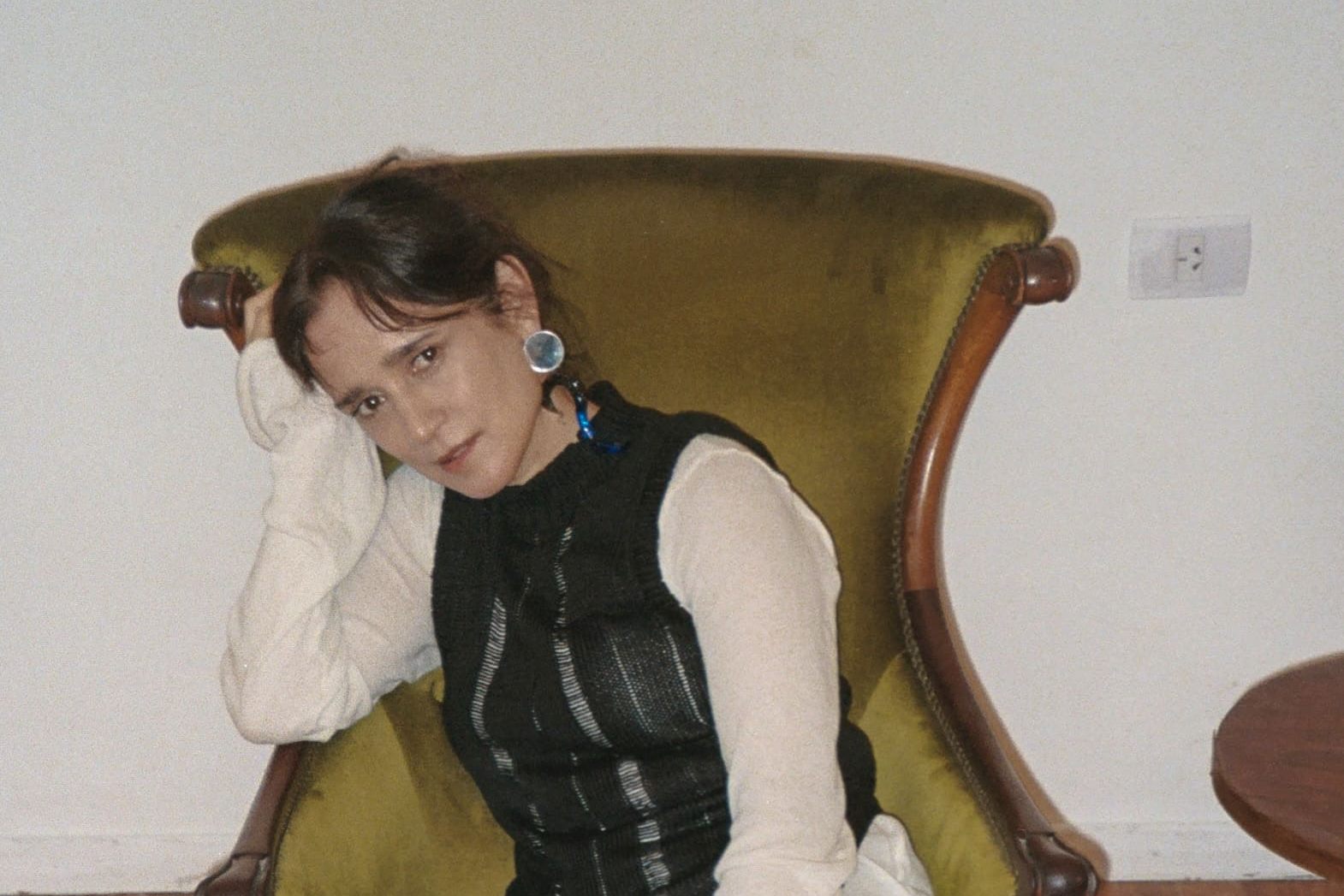 La artista Julieta Vengas sentada en un sofá individual antiguo.